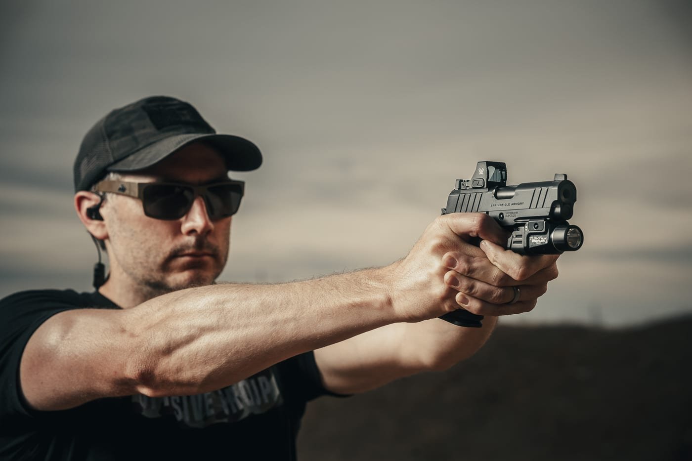 A photograph of the author firing the Springfield Armory 1911 DS Prodigy Compact pistol with a 3.5-inch barrel at a shooting range. The pistol is equipped with a red dot sight and weapon light, showcasing its versatility for defensive scenarios. The author maintains a solid two-handed grip, emphasizing the pistol’s ergonomic design and manageable recoil. Brass is visible ejecting from the slide, capturing the moment of live fire. The photo highlights the Prodigy Compact’s compact size, accuracy, and suitability for concealed carry.